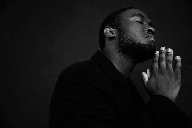 black man with folded hands praying